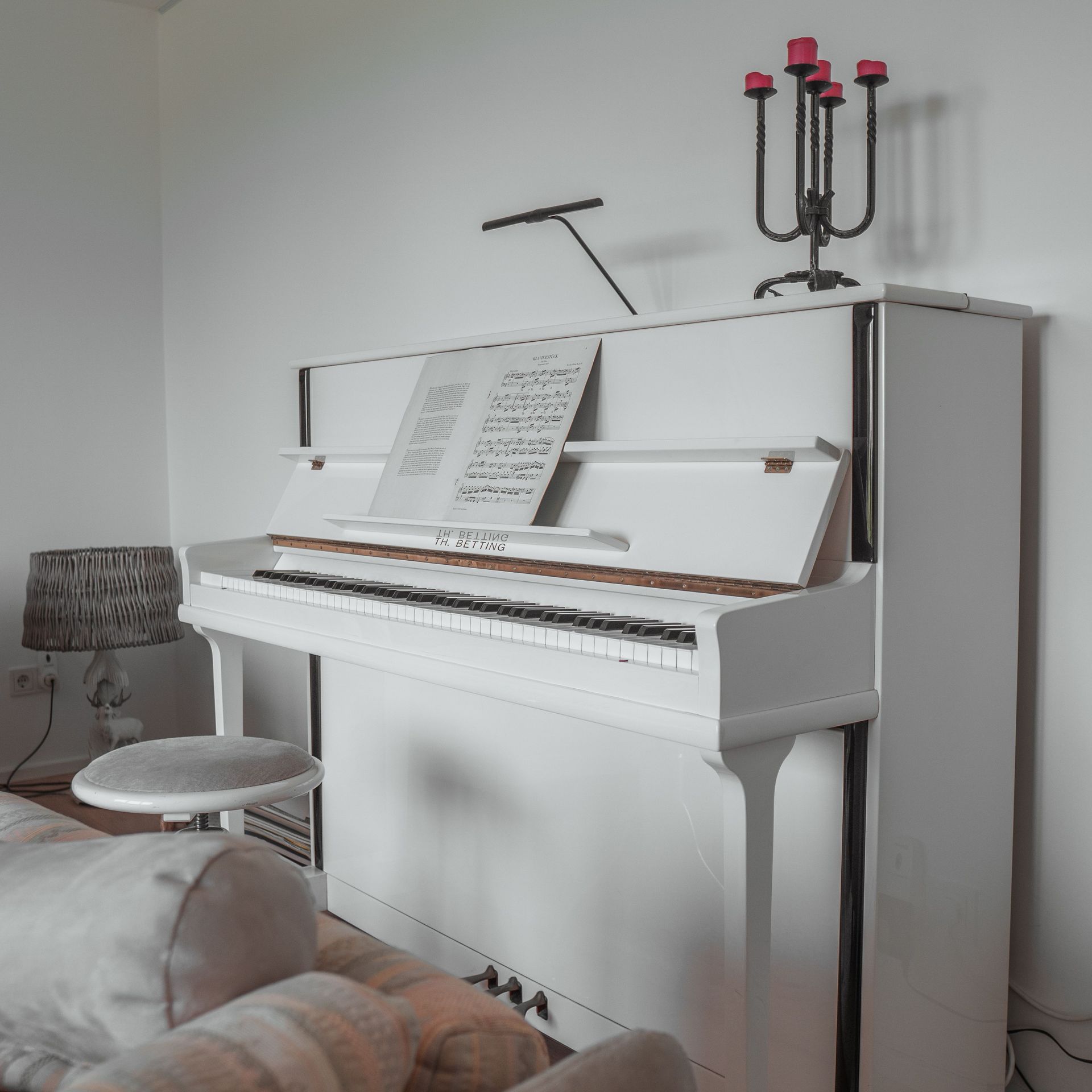 A classic white piano in a stylish living room with sheet music and decor.